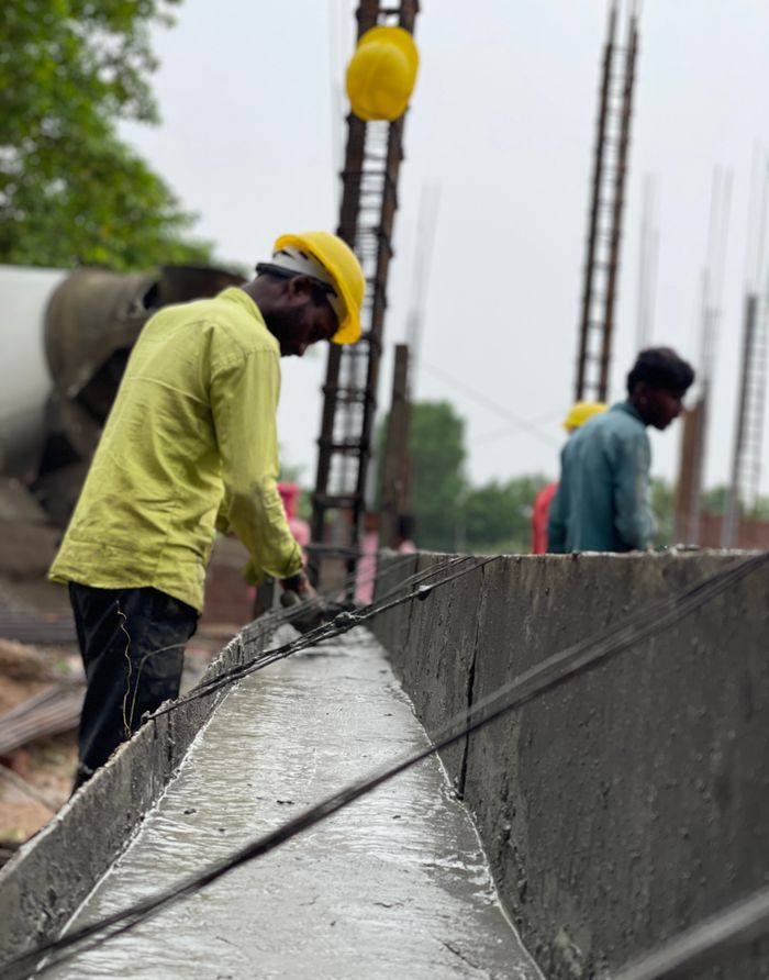Men at work on a construction site, focusing on concrete tasks, wearing safety gear.