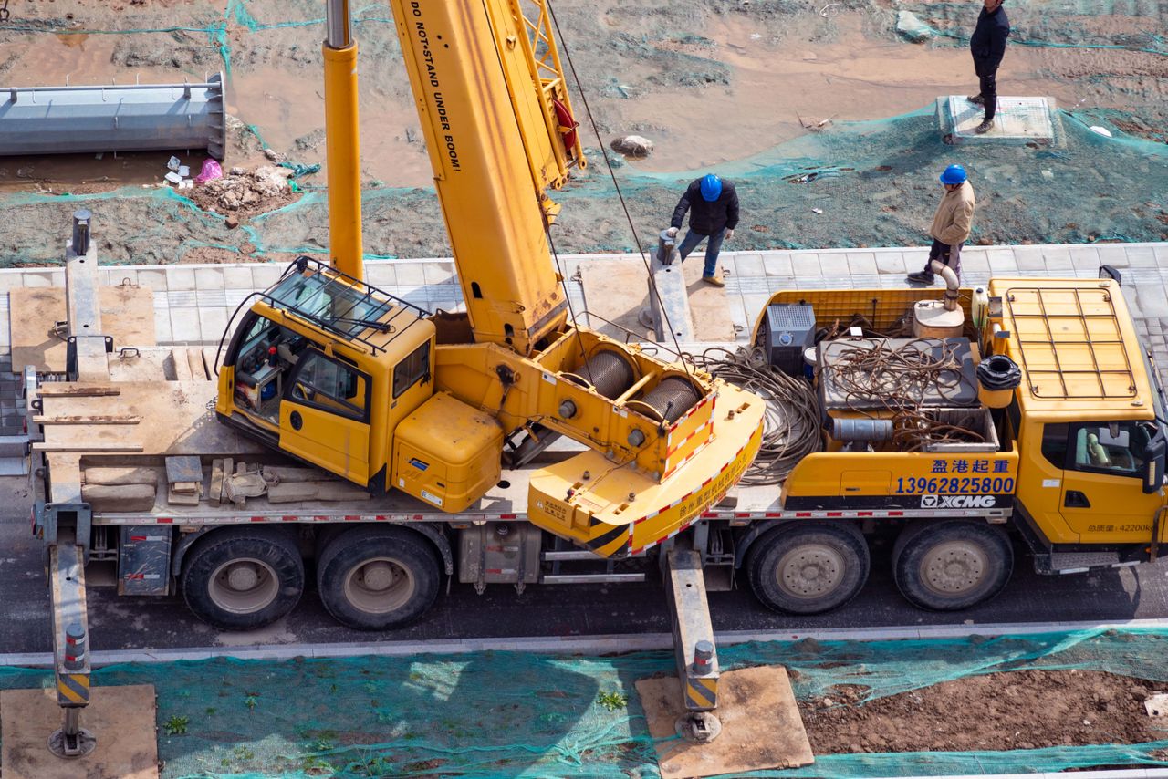 Aerial shot of a construction site showcasing a yellow crane and workers in action.