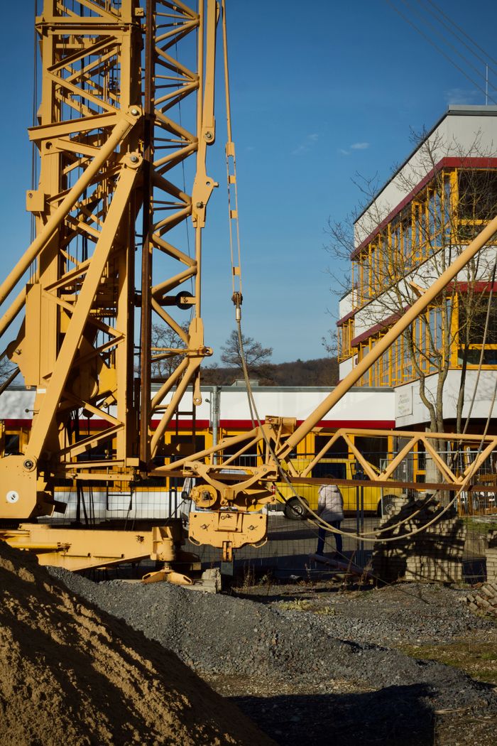 A large construction crane at an urban worksite with clear blue skies, captured during the day.